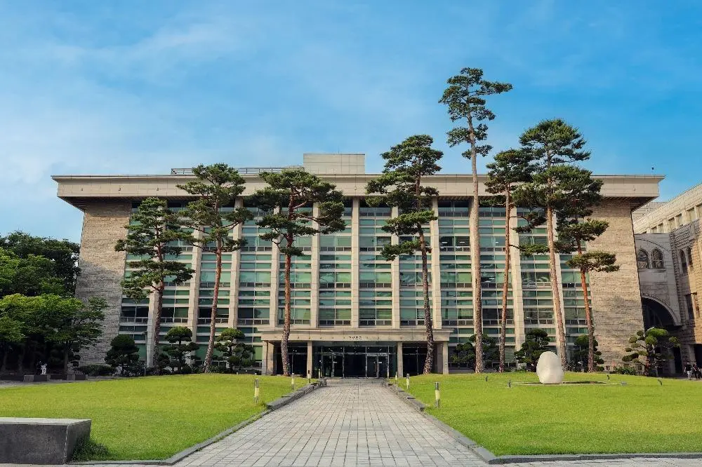 Korea University campus building with green lawn and trees in Seoul